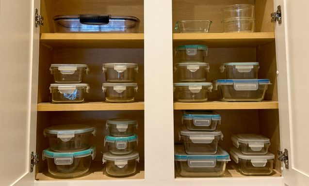 A cabinet with various glass storage containers organized on wooden shelves.