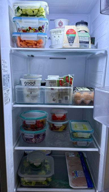 A neatly organized refrigerator with various containers of fruits, vegetables, and eggs.