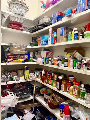 Messy pantry filled with various jars, containers, and food items on shelves.