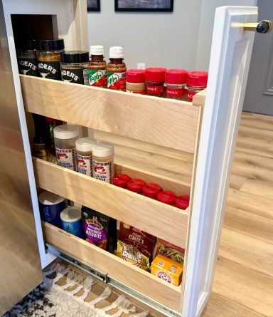 Narrow cabinet with shelves holding various spice jars and condiments.