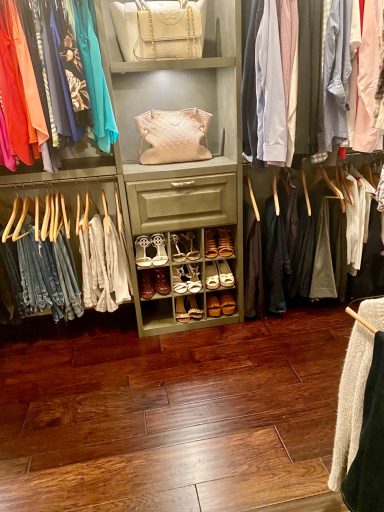 A well-organized closet featuring clothing, shoes, and accessories on wooden shelves.
