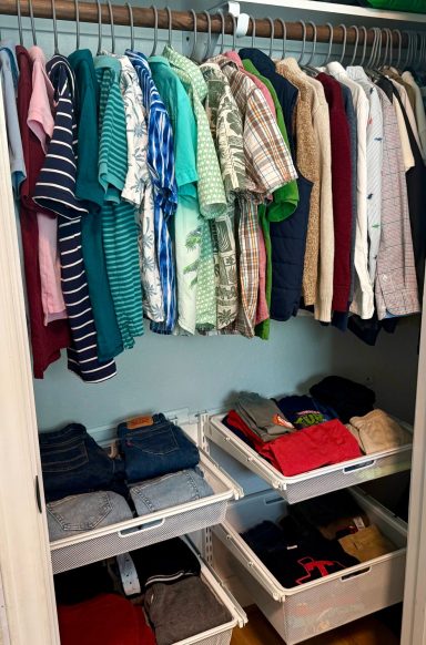 Organized closet with hanging shirts and neatly folded pants in storage bins.