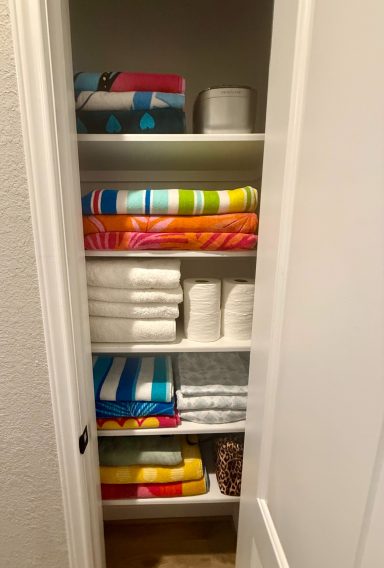 Neatly organized shelves with colorful towels, toilet paper, and miscellaneous items.