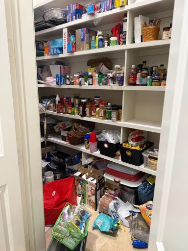 A disorganized pantry filled with various food items and containers on shelves.