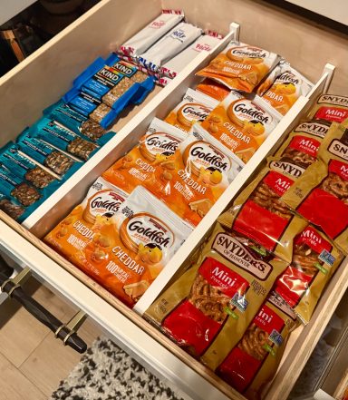 Organized drawer containing snacks, including granola bars and various chips.