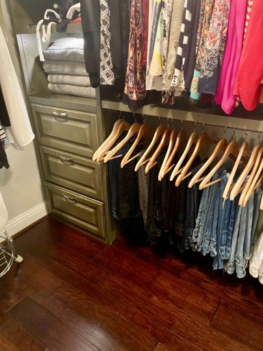 A well-organized closet with hanging clothes and a stack of folded towels.