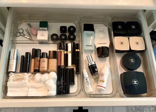 Organized drawer with various makeup products, cotton pads, and skincare items.
