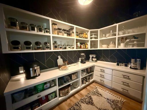 Modern kitchen with white cabinets, jars, and appliances, featuring a cozy layout.