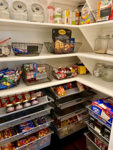 Organized pantry with baskets of snacks, jars, and various food items on multiple shelves.